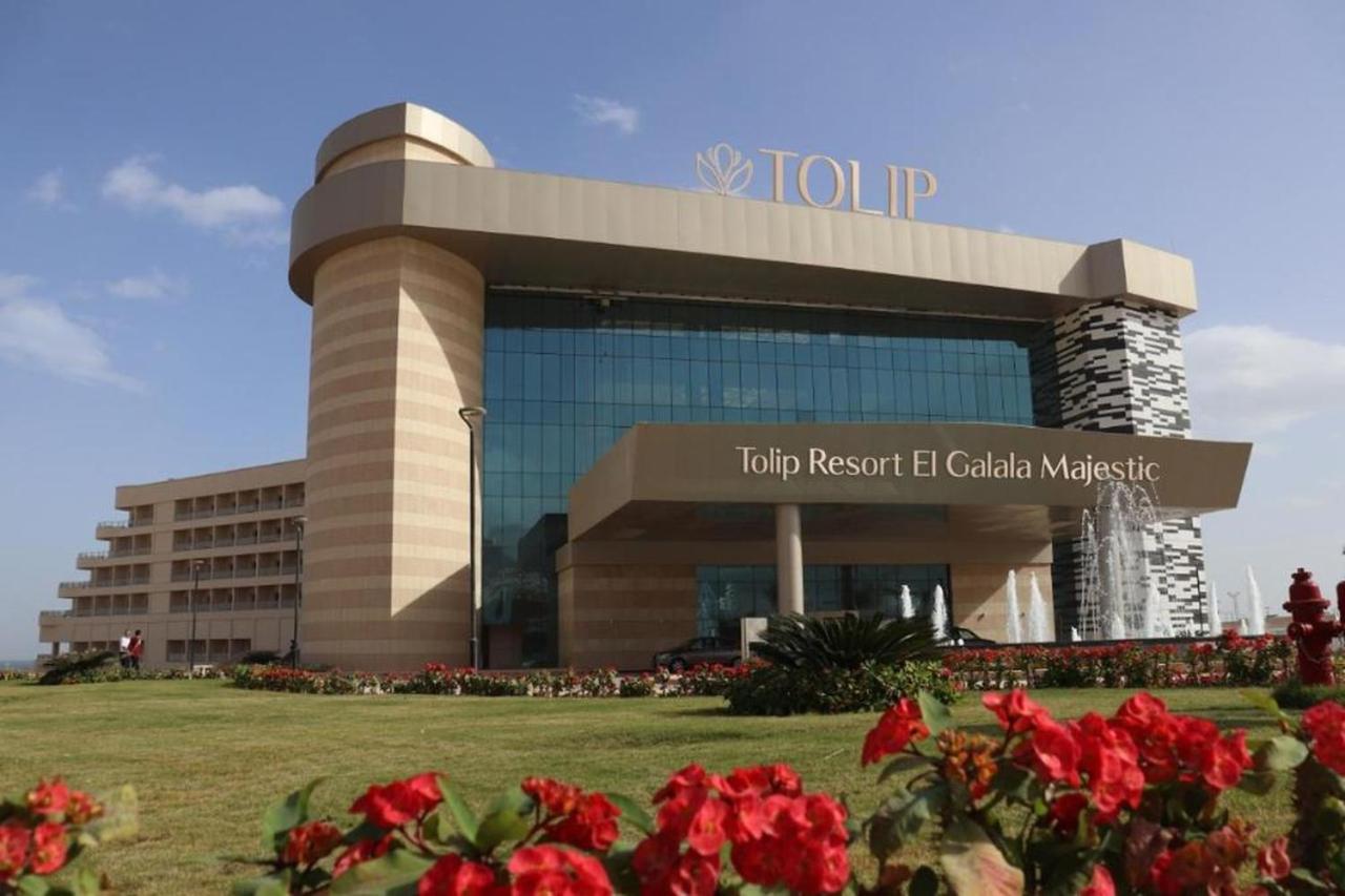 Tolip Resort El Galala Majestic Ajn-Szuhna Kültér fotó The photo shows a modern hotel building named "Tolip Resort El Galala Majestic." The structure features a distinctive architectural design with large glass windows and a prominent entrance. Surrounding the building are well-maintained lawns and vibra