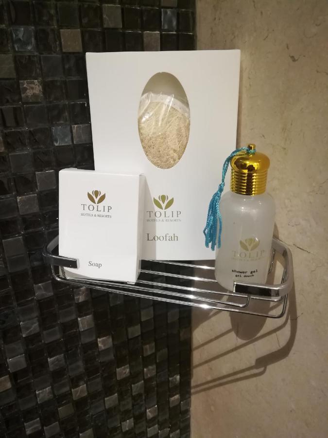 Tolip Resort El Galala Majestic Ajn-Szuhna Kültér fotó The photo shows a small metal shelf containing three items related to personal care. 

1. **Soap**: A white box labeled "TOLIP" with the word "Soap" visible on the front.
2. **Loofah**: A package with the same "TOLIP" branding, containing loofah.
3. 