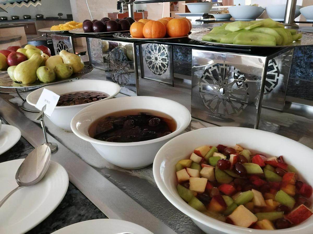 Tolip Resort El Galala Majestic Ajn-Szuhna Kültér fotó The photo shows a buffet-style arrangement of various fruits and fruit dishes. In the foreground, there are several bowls containing different types of fruit. One bowl has a fruit salad made with diced apples, green apples, and possibly other fruits.